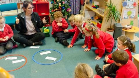 Teacher and her early years pupils sat on the carpet teaching and learning