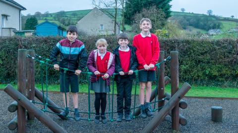 Girl and 3 boys stood on the rope bridge in the playground