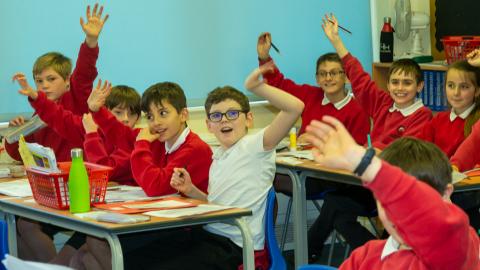 Children with hands up in a lesson
