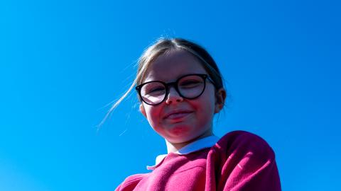 Girl in the foreground of a bright blue sky