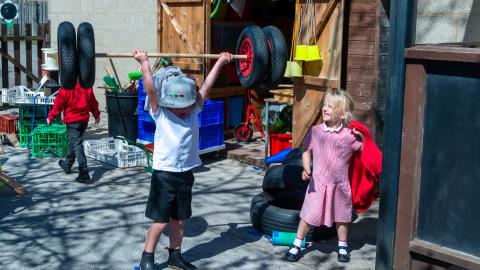 Young early years boy pretends to be a weightlifter