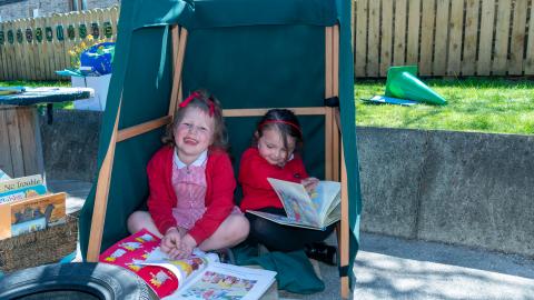 Two girls reading books in the early years playground